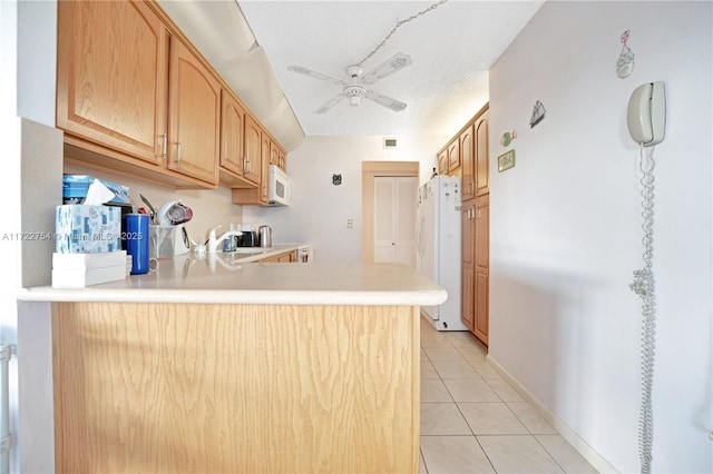 kitchen with a textured ceiling, white appliances, kitchen peninsula, and light tile patterned floors