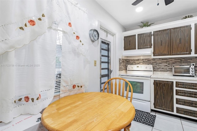 kitchen with dark brown cabinets, electric range, light tile patterned floors, and backsplash