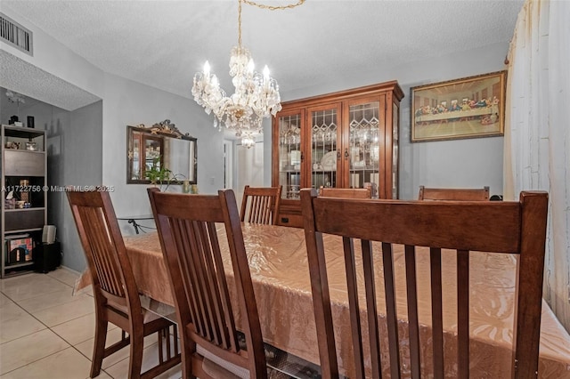 tiled dining area featuring a notable chandelier and a textured ceiling