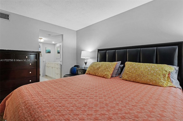 bedroom with ensuite bathroom and a textured ceiling