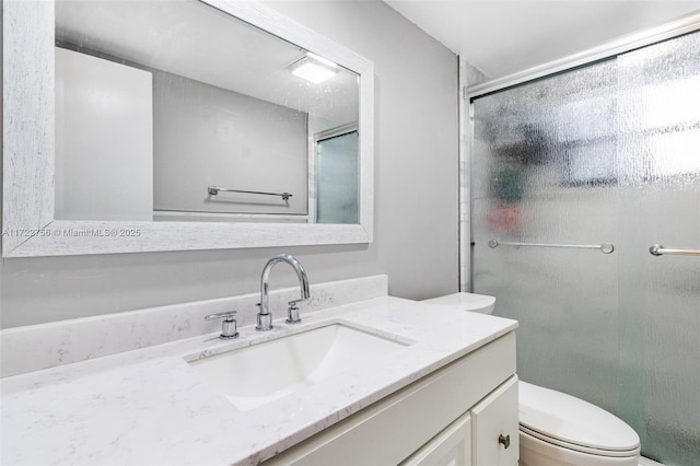 bathroom with vanity, a shower with shower door, and toilet