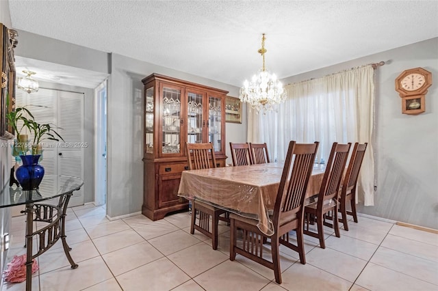 dining space featuring light tile patterned floors, a textured ceiling, and an inviting chandelier