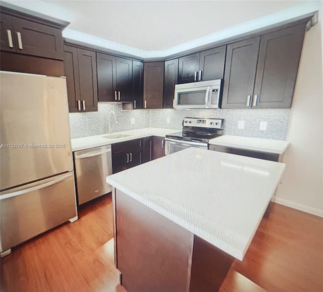 kitchen featuring backsplash, a kitchen breakfast bar, sink, light hardwood / wood-style flooring, and stainless steel appliances