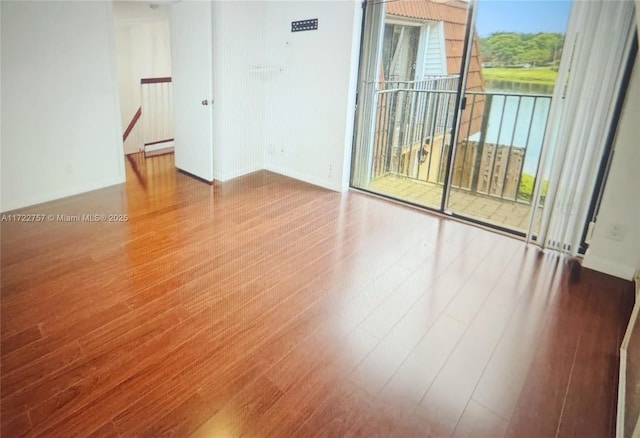 unfurnished room with hardwood / wood-style flooring, plenty of natural light, and a baseboard heating unit