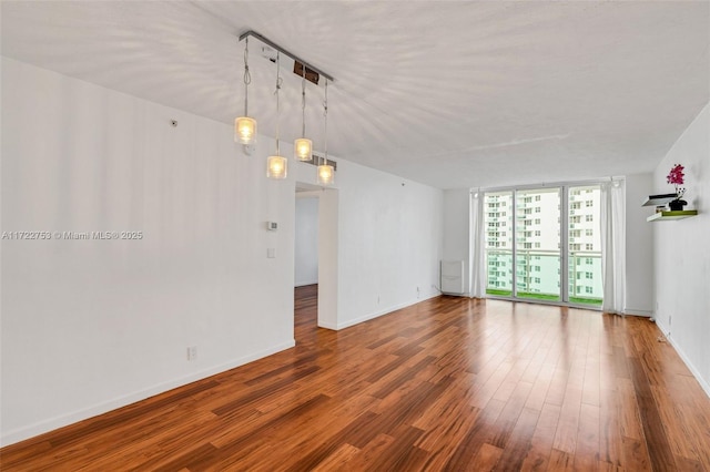 unfurnished room featuring baseboards, floor to ceiling windows, and wood finished floors