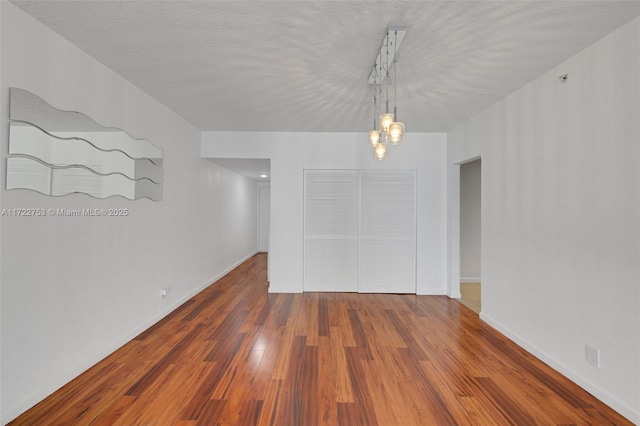 spare room with baseboards and wood finished floors