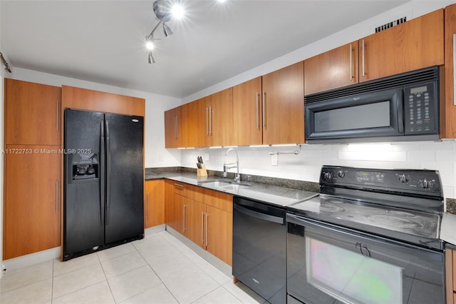 kitchen with black appliances, brown cabinetry, dark countertops, and a sink