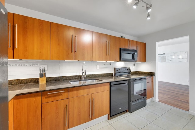 kitchen featuring tasteful backsplash, dark stone counters, a sink, and black appliances