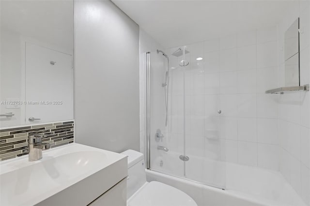 full bath with combined bath / shower with glass door, toilet, backsplash, and vanity