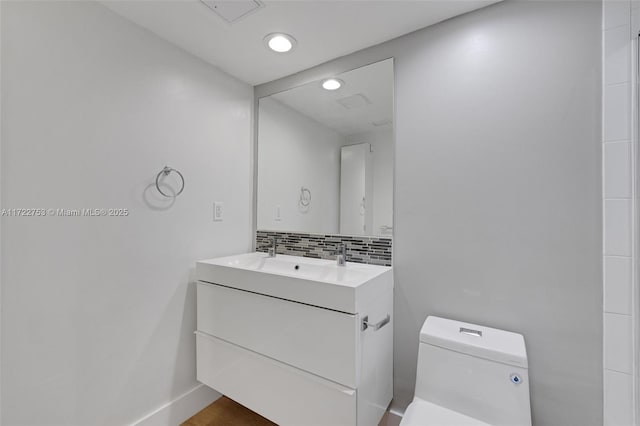 bathroom featuring recessed lighting, backsplash, toilet, vanity, and baseboards