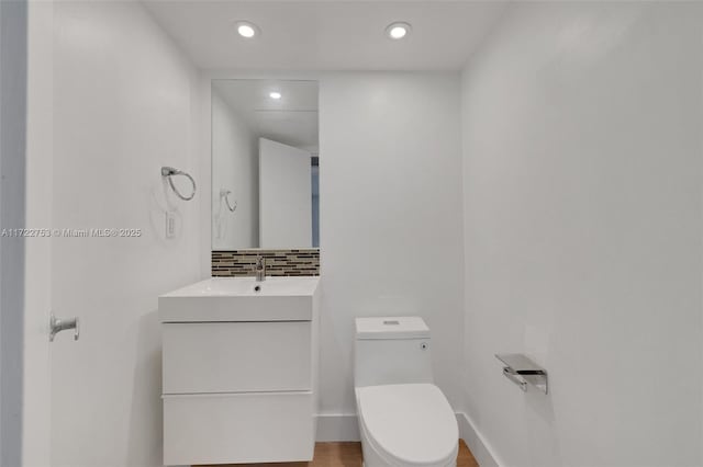 half bath with recessed lighting, backsplash, toilet, vanity, and baseboards