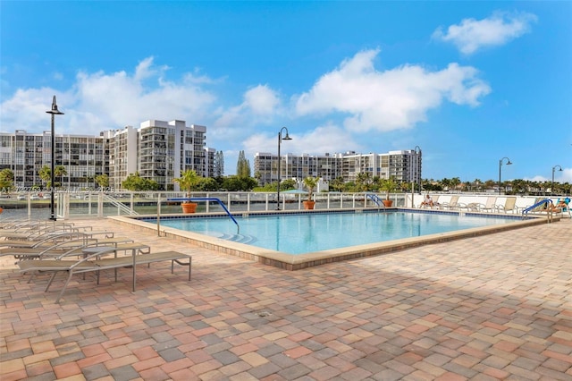 community pool featuring fence, a city view, and a patio