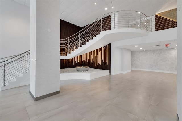 staircase featuring baseboards and a high ceiling