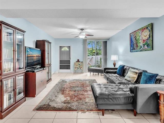 living room with ceiling fan, a textured ceiling, and light tile patterned flooring