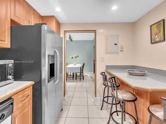 kitchen featuring dishwasher, electric panel, a kitchen bar, stainless steel refrigerator with ice dispenser, and light tile patterned floors