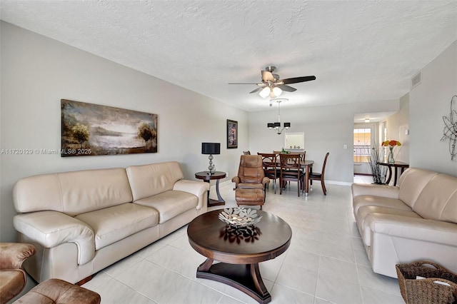 living room featuring ceiling fan, light tile patterned flooring, and a textured ceiling