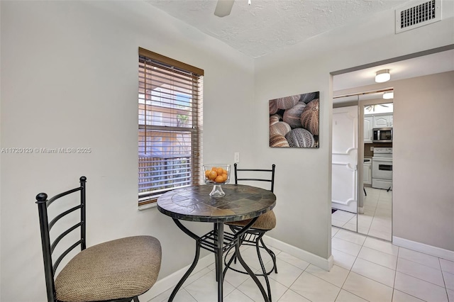 dining area featuring light tile patterned floors, a textured ceiling, and ceiling fan