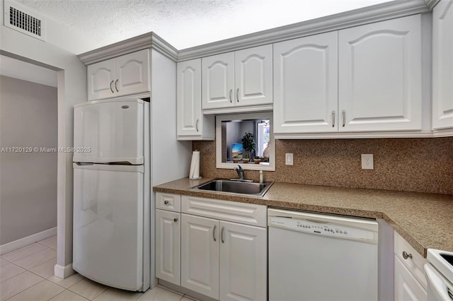 kitchen featuring backsplash, white appliances, sink, light tile patterned floors, and white cabinets