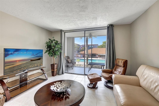 living room with ceiling fan, a wall of windows, and a textured ceiling