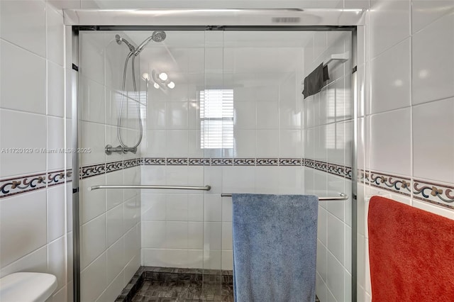 bathroom with toilet, tile walls, and walk in shower