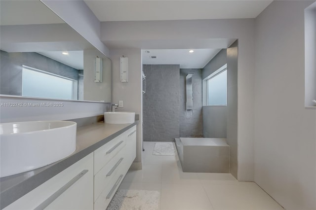 bathroom with vanity, tile patterned flooring, a healthy amount of sunlight, and tiled shower