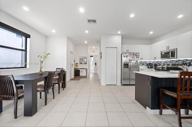 kitchen with white cabinets, appliances with stainless steel finishes, backsplash, and light tile patterned floors