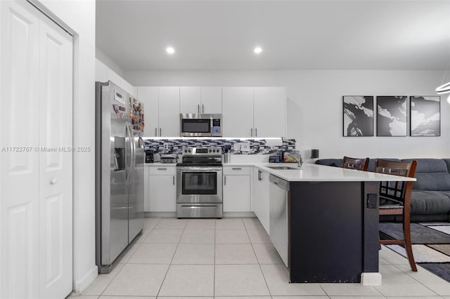 kitchen with white cabinetry, sink, stainless steel appliances, kitchen peninsula, and light tile patterned floors