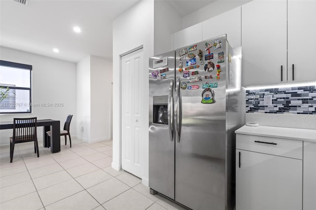 kitchen featuring white cabinets, stainless steel fridge with ice dispenser, backsplash, and light tile patterned floors