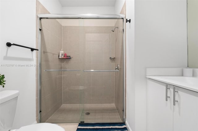 bathroom with vanity, toilet, and a shower with door