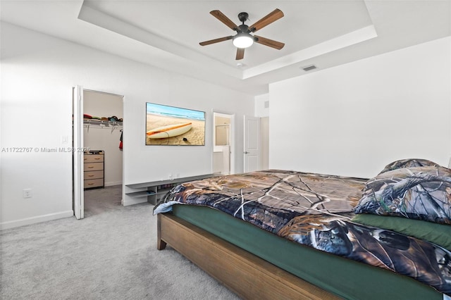 bedroom featuring a closet, a tray ceiling, a spacious closet, and ceiling fan