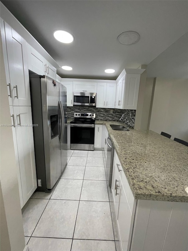 kitchen featuring kitchen peninsula, sink, white cabinets, and stainless steel appliances