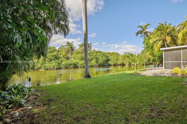 view of yard featuring a sunroom and a water view