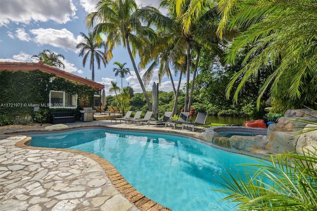 view of pool featuring a grill, an in ground hot tub, and a patio