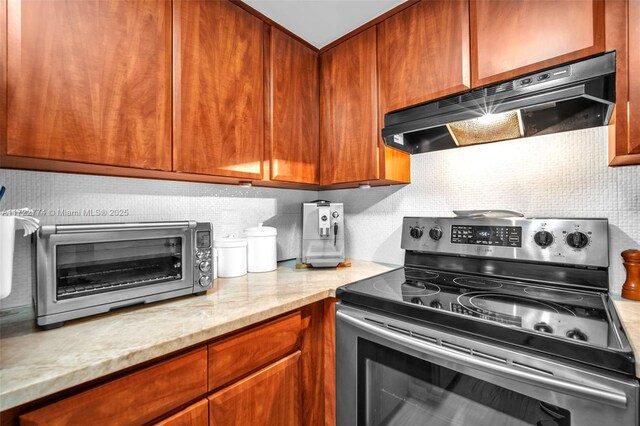 kitchen featuring stainless steel electric stove, light stone countertops, and decorative backsplash