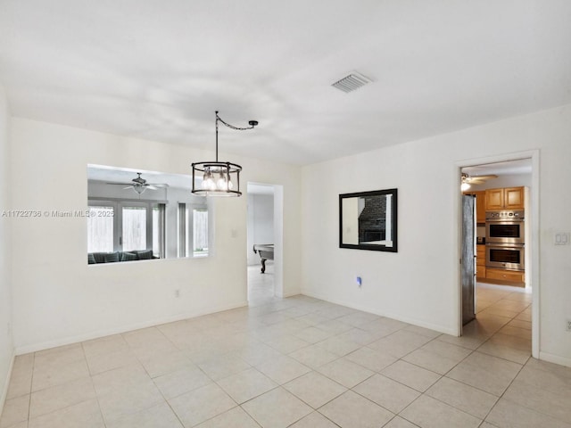 unfurnished room with ceiling fan with notable chandelier and light tile patterned flooring