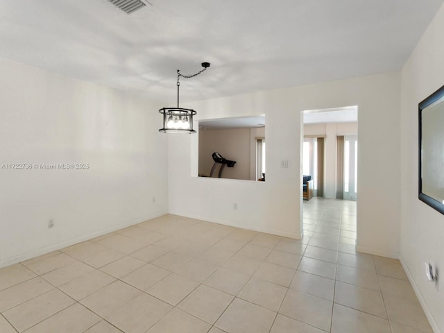 tiled spare room with a notable chandelier