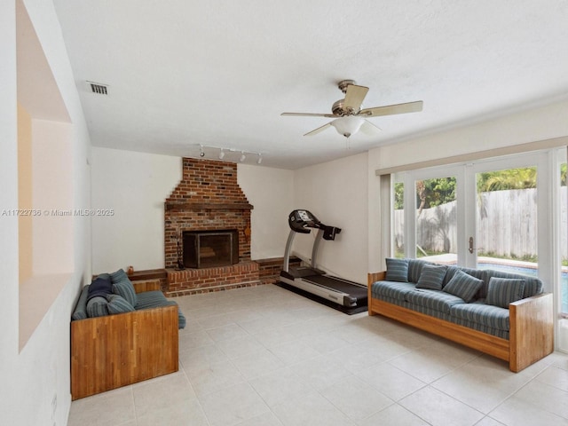 tiled living room featuring a fireplace, ceiling fan, rail lighting, and french doors