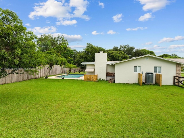 view of yard with central air condition unit and a fenced in pool