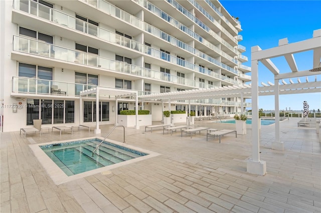 view of swimming pool with a community hot tub and a pergola