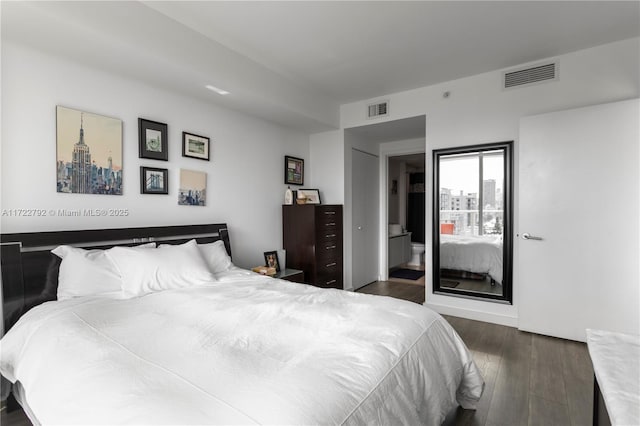 bedroom with connected bathroom and dark hardwood / wood-style floors