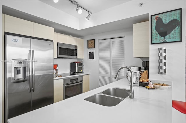 kitchen featuring appliances with stainless steel finishes, rail lighting, and sink