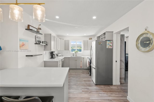 kitchen featuring gray cabinetry, stainless steel appliances, sink, pendant lighting, and a breakfast bar area