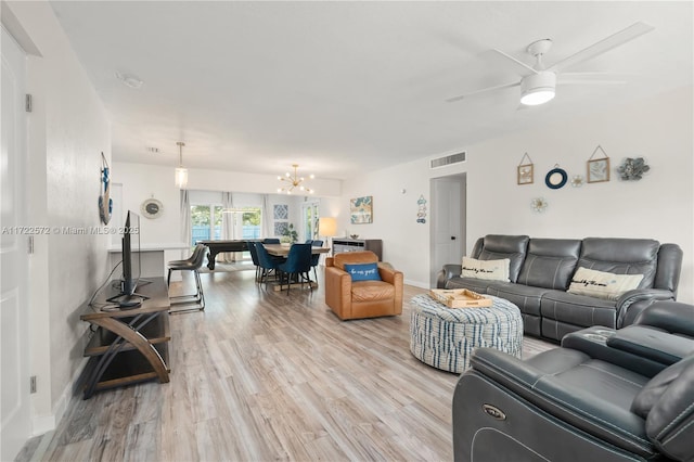 living room with ceiling fan with notable chandelier and light wood-type flooring