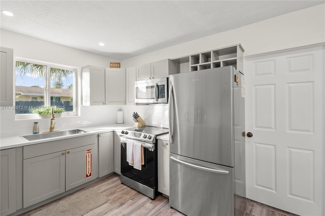 kitchen with gray cabinets, sink, appliances with stainless steel finishes, and light hardwood / wood-style flooring