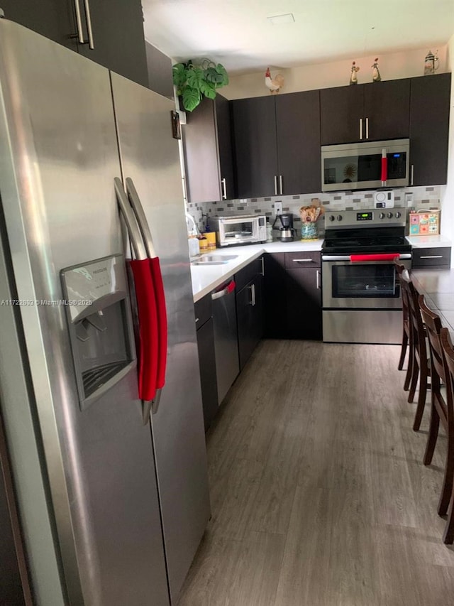 kitchen featuring appliances with stainless steel finishes, tasteful backsplash, and light hardwood / wood-style flooring