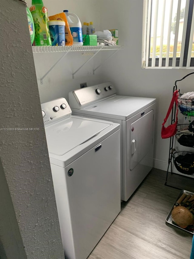 clothes washing area featuring washer and clothes dryer and light hardwood / wood-style flooring