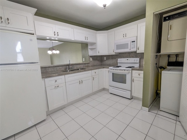 kitchen with white cabinetry, stacked washing maching and dryer, sink, and white appliances