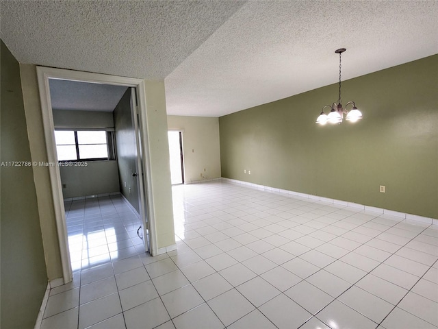 empty room featuring a notable chandelier, a textured ceiling, and light tile patterned floors