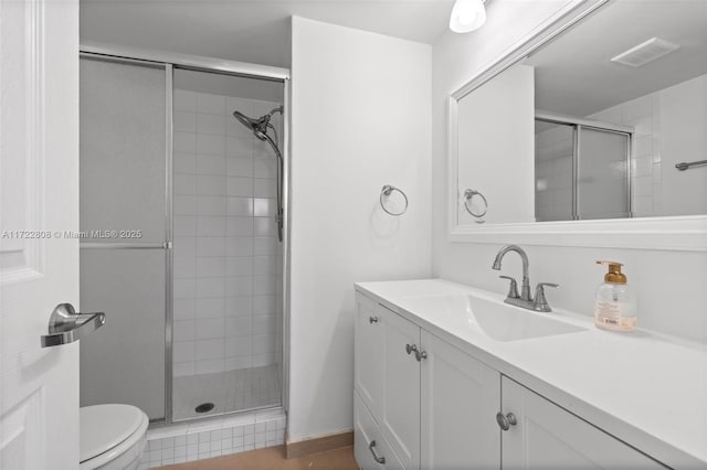 bathroom featuring vanity, toilet, and a shower with shower door