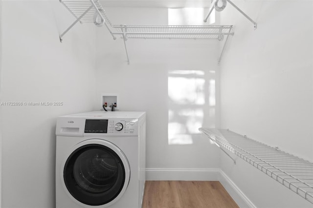 washroom with hardwood / wood-style flooring and washer / dryer